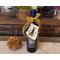 A bottle of wine with a handmade birch bark gift tag tied to the bottle with a yellow bow.
